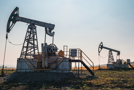 oil pumps operate in a vast field under a clear blue sky at midday in rural area