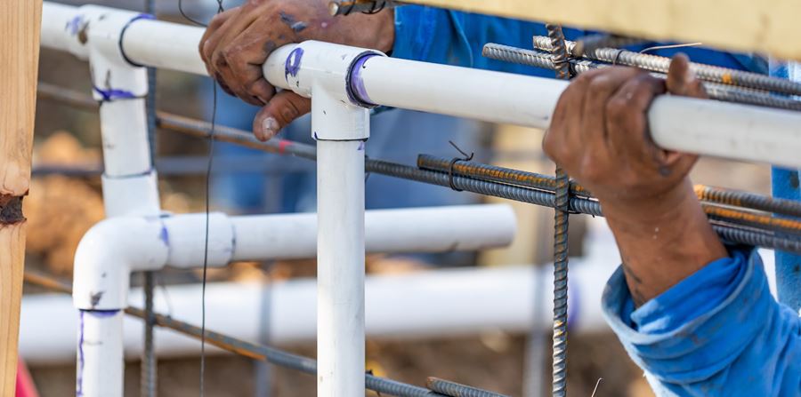 plumber installing pvc pipe at construction site