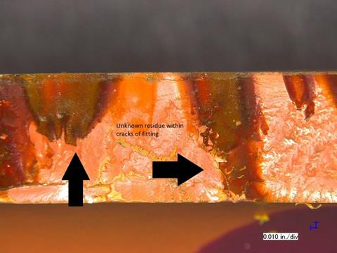 Microscopic view documenting residue within cracks in the failed fitting