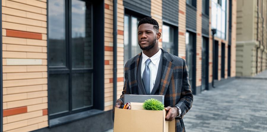 office worker holding box with things and leaving office building